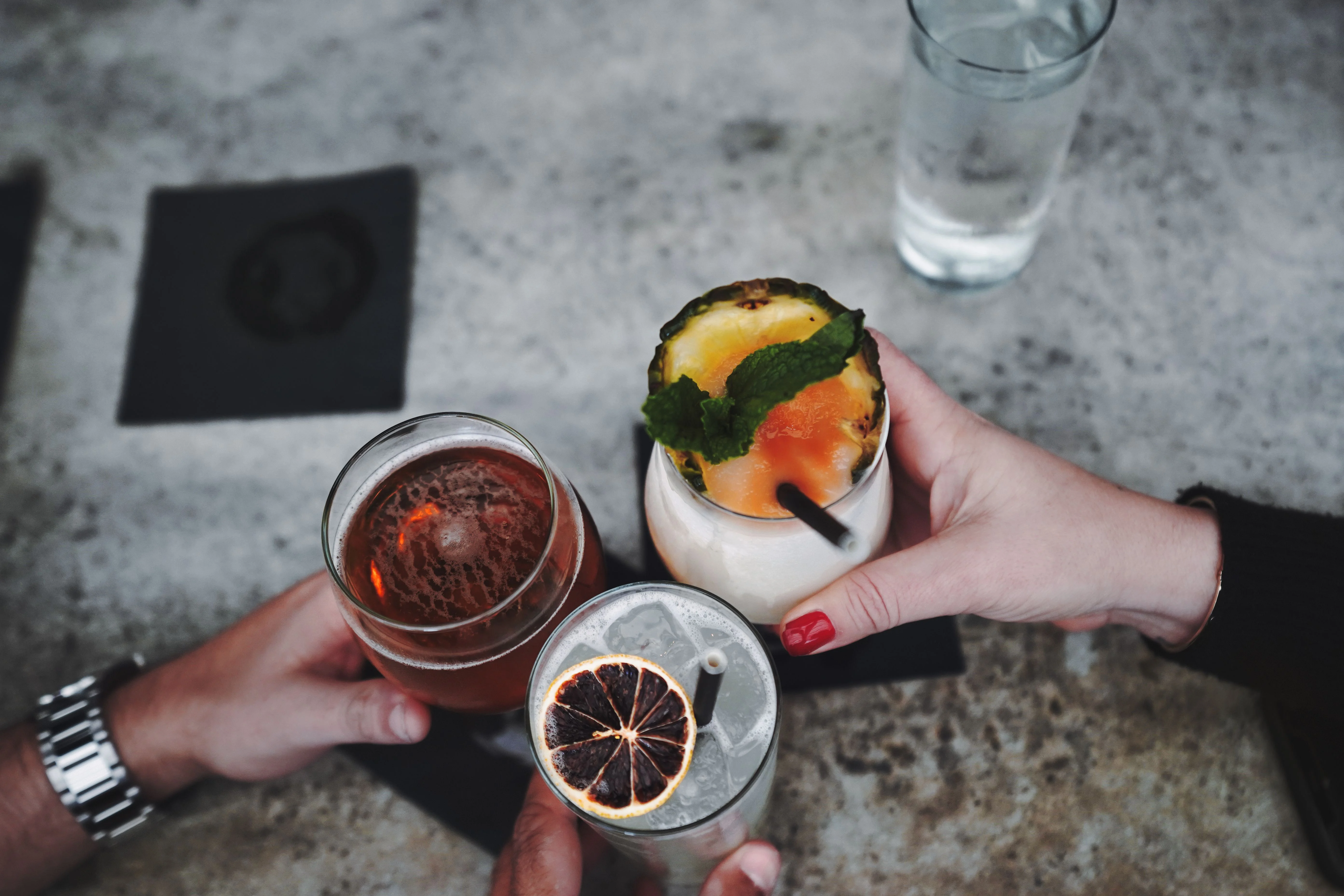 Tre persone brindano con cocktail durante un aperitivo